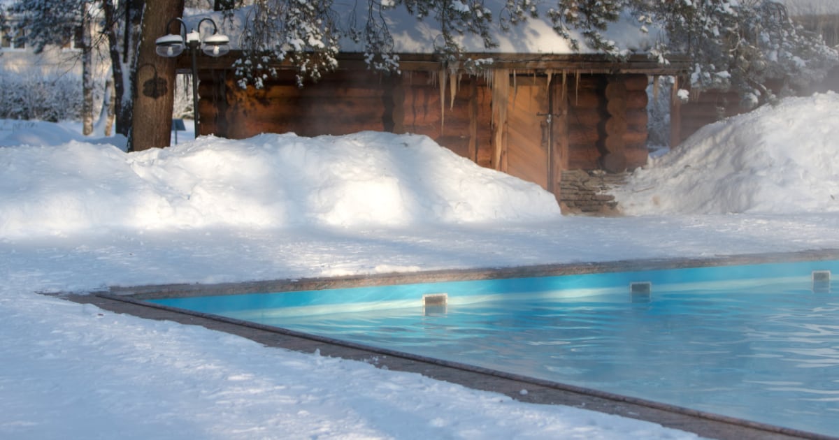 Warm swimming pool with blue water and wooden bath in sunny winter weather.
